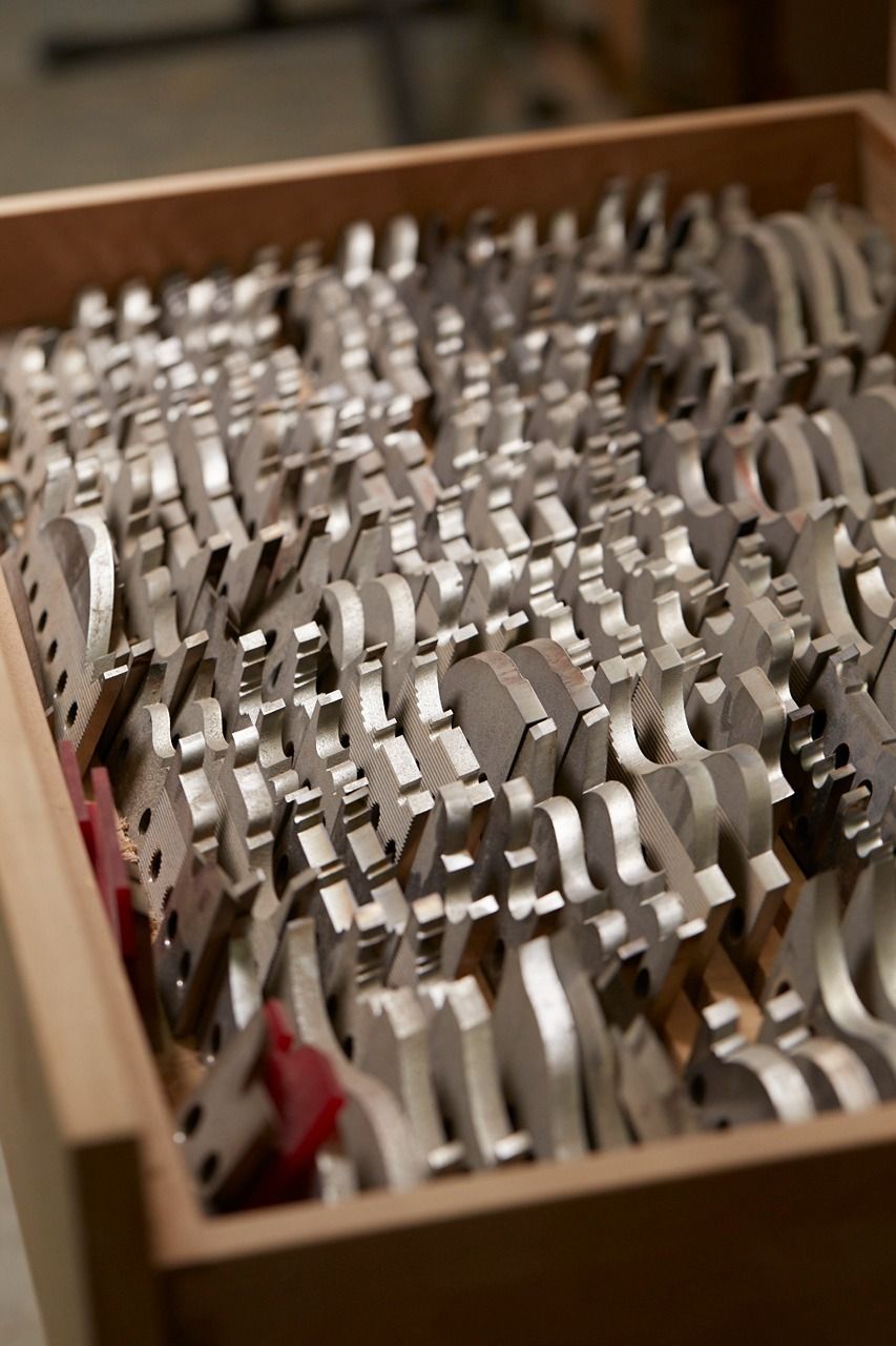 A wooden drawer filled with rows of silver metal tools, likely wrenches, with some red accents.