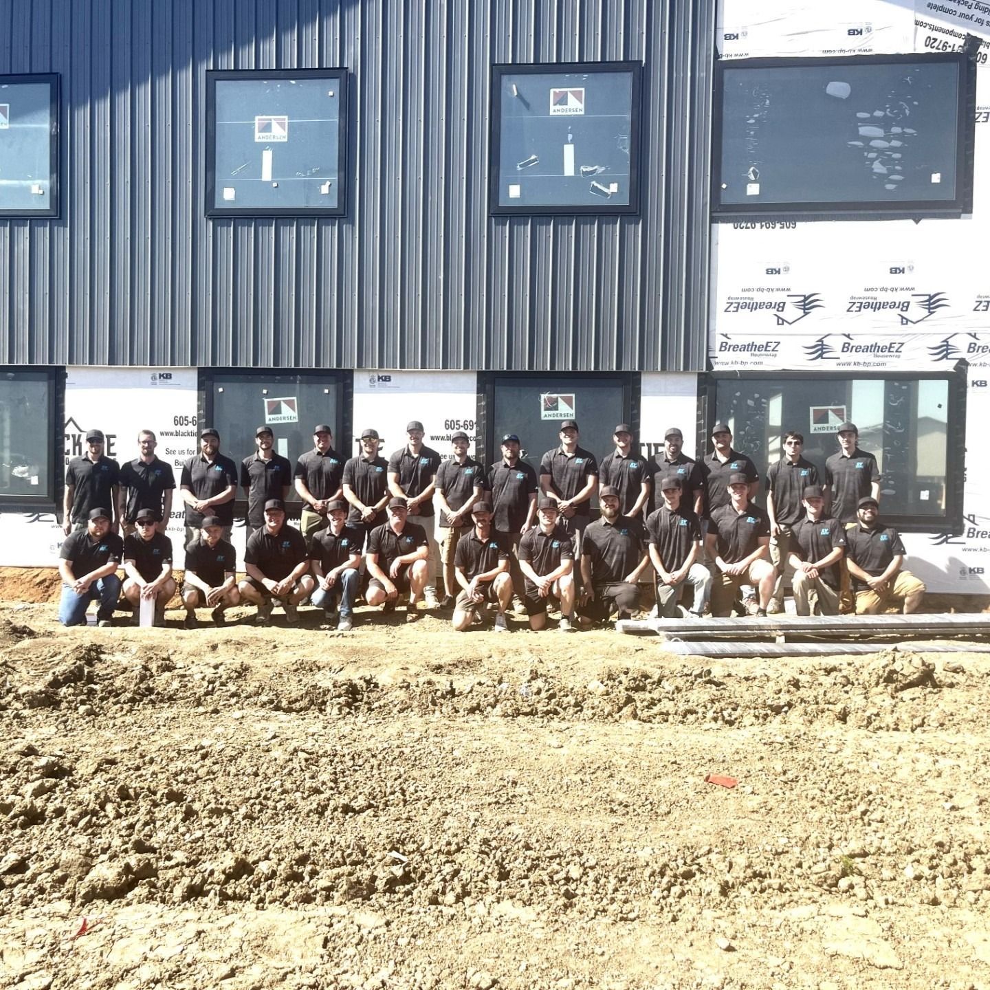A group of men are posing for a picture in front of a building under construction