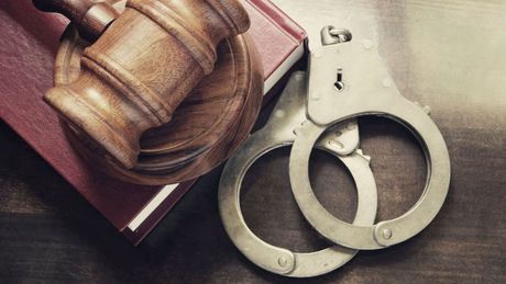 A judge 's gavel and handcuffs are sitting on top of a book.