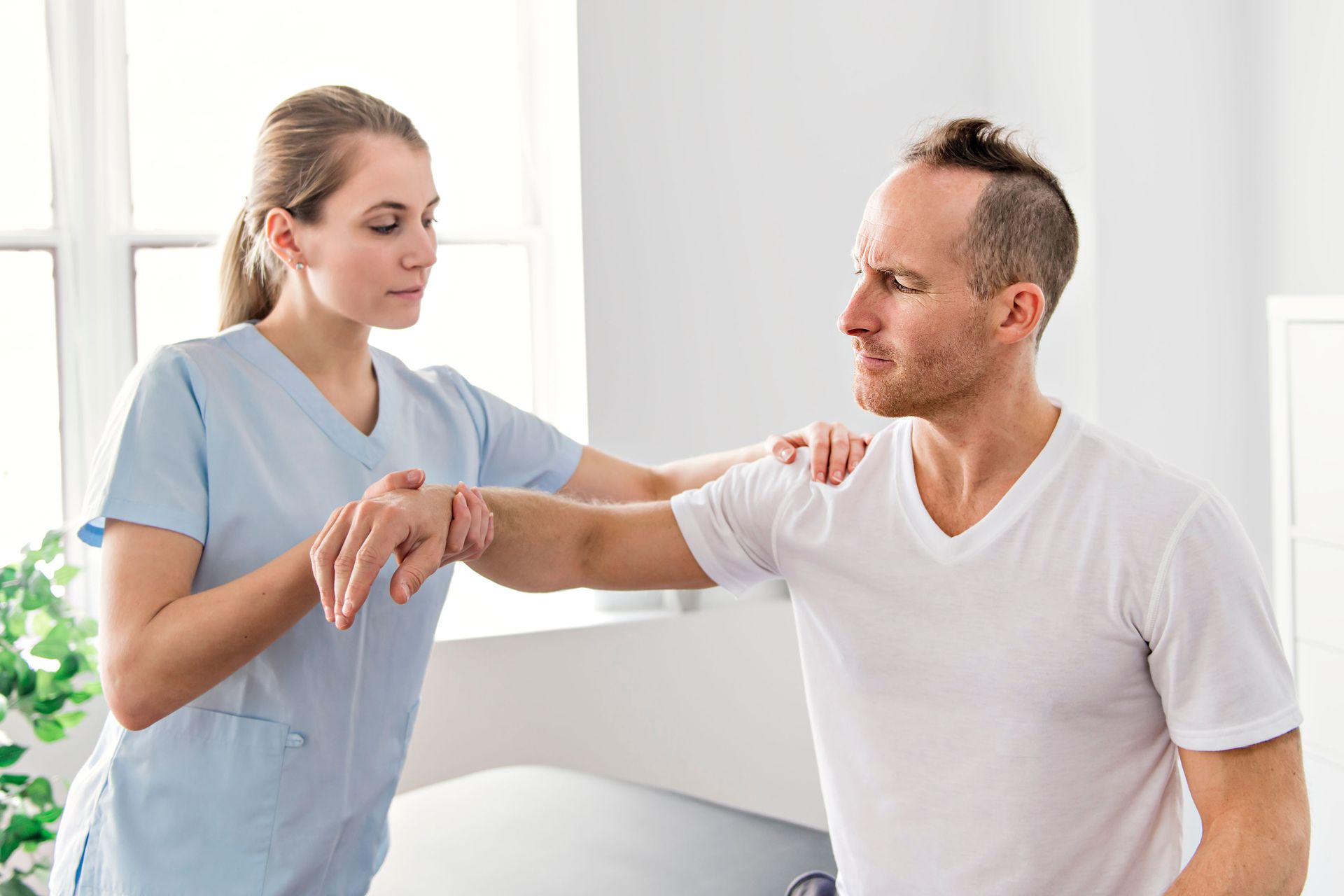 A chiropractor examines a patient's arm and shoulder