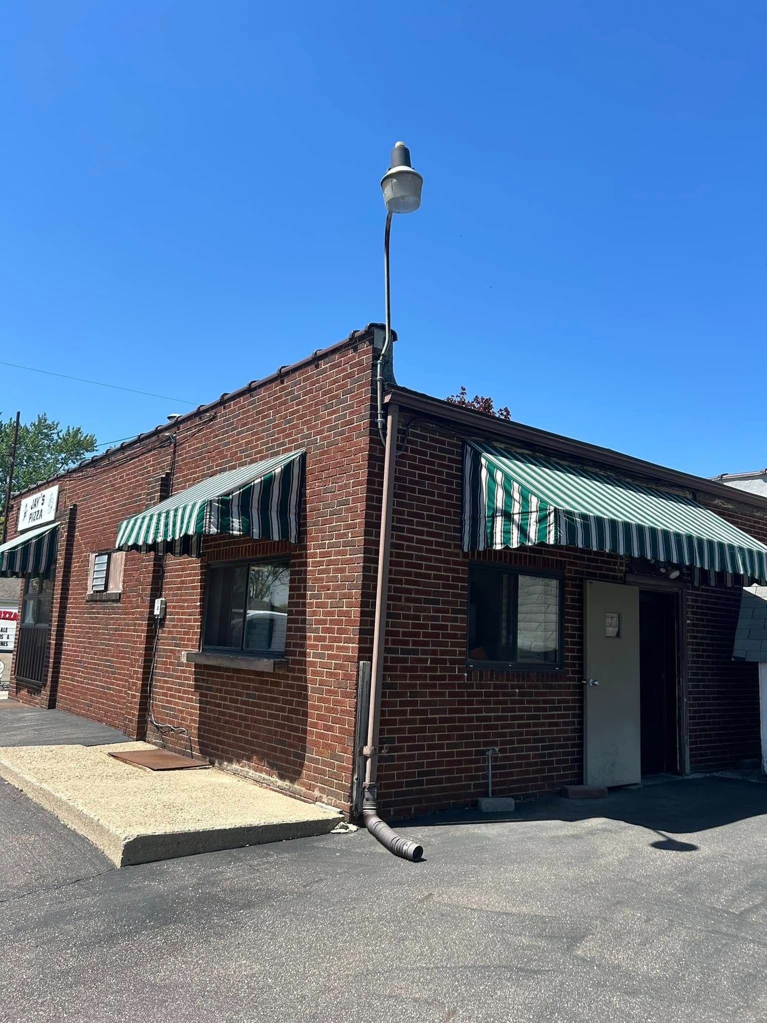 Brick building with green and white striped awnings, under a clear blue sky.