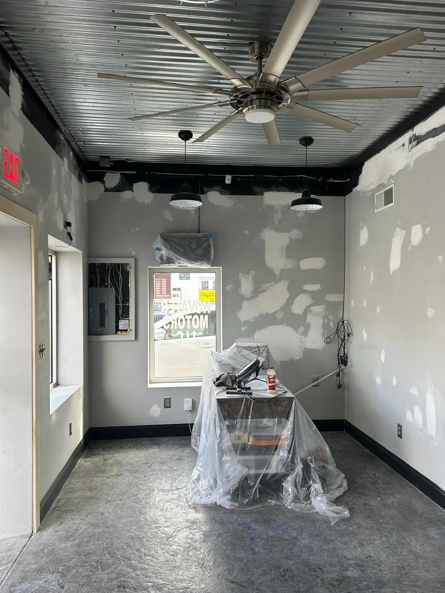 Interior of a building under renovation with gray walls, a metal ceiling, and a desk covered in plastic.