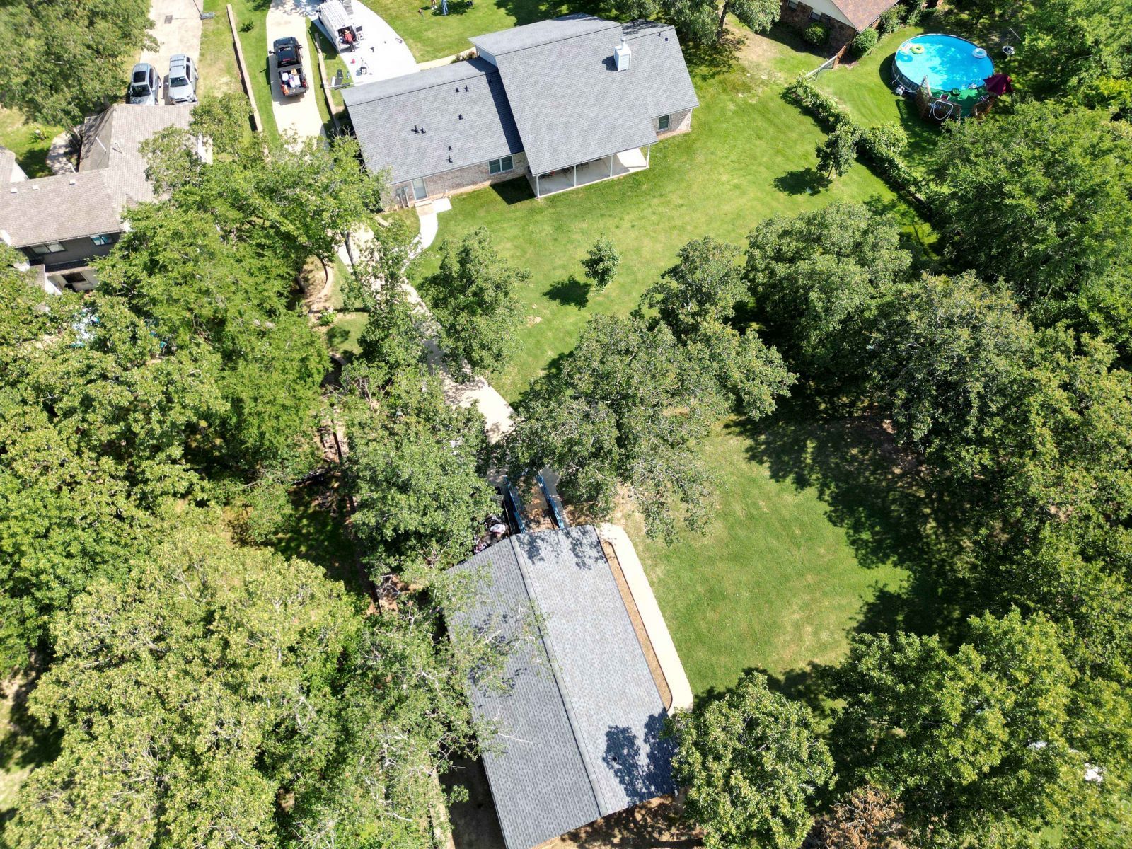 An aerial view of a house surrounded by trees and grass