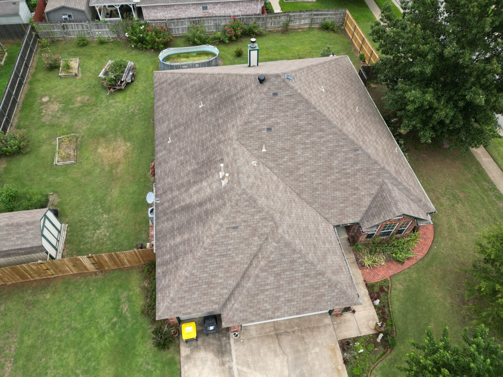 An aerial view of a house with a roof and a pool in the backyard.