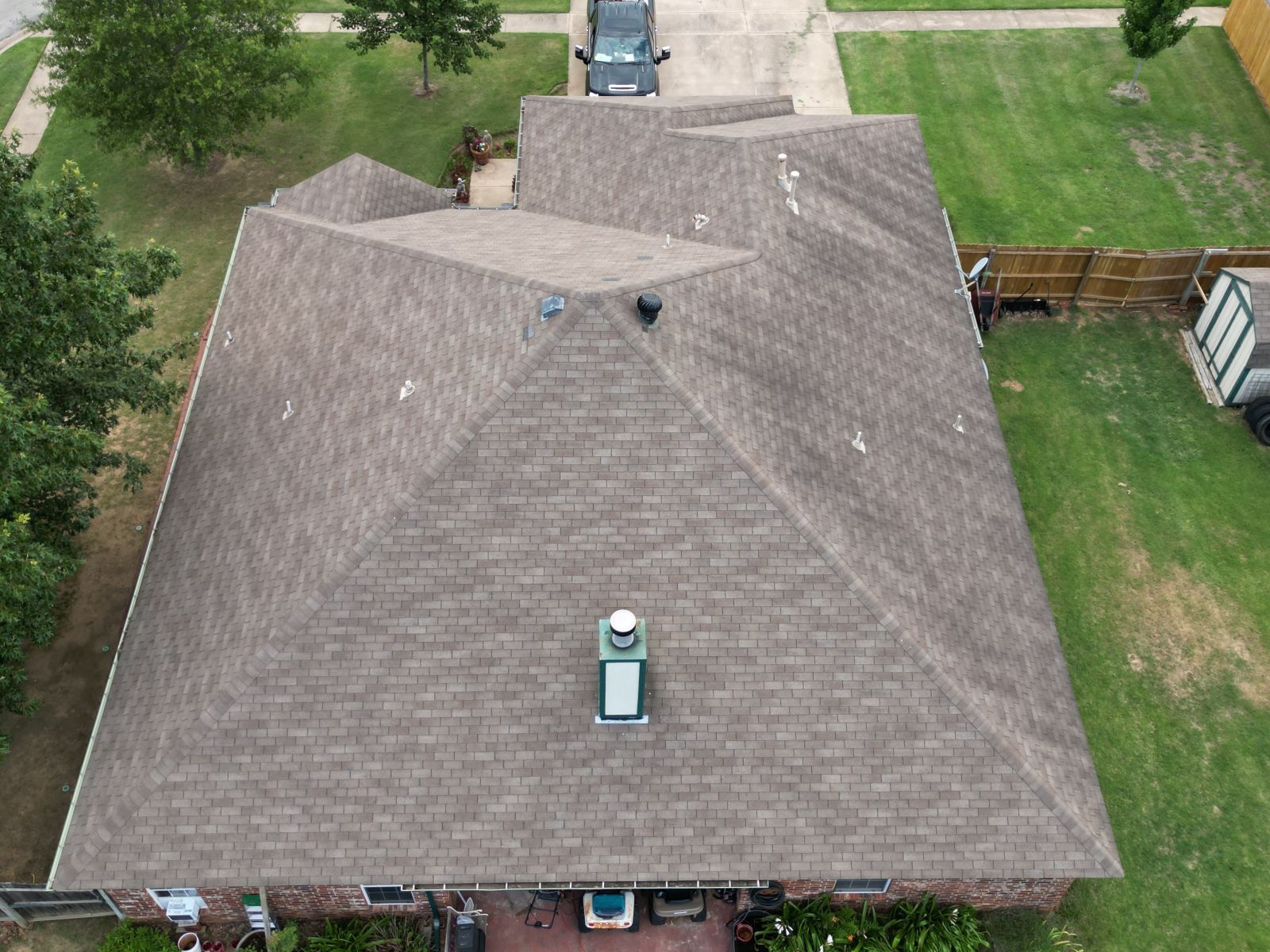 An aerial view of a house with a roof and a car parked in the driveway.