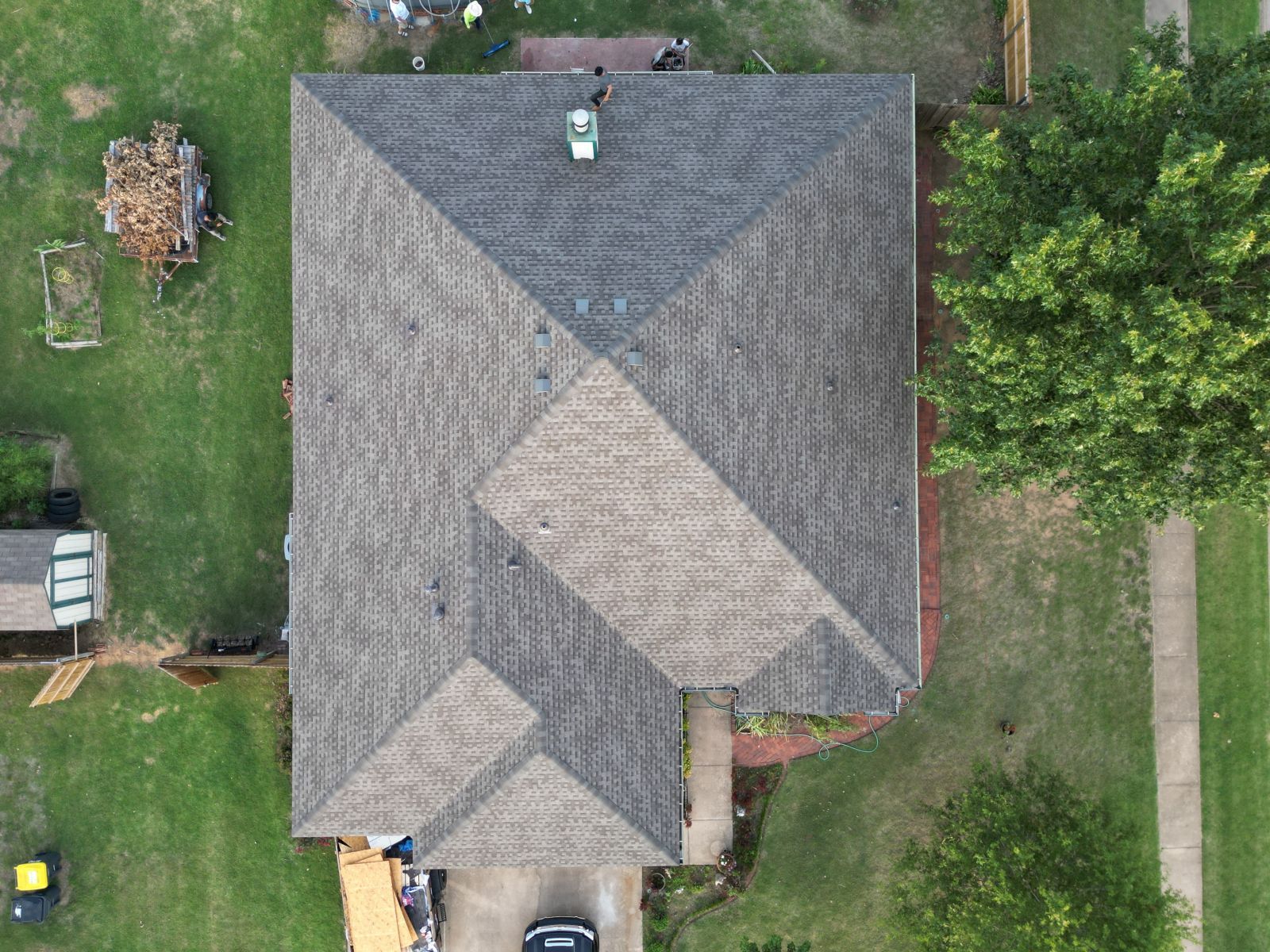 An aerial view of a house with a roof and a car parked in front of it.