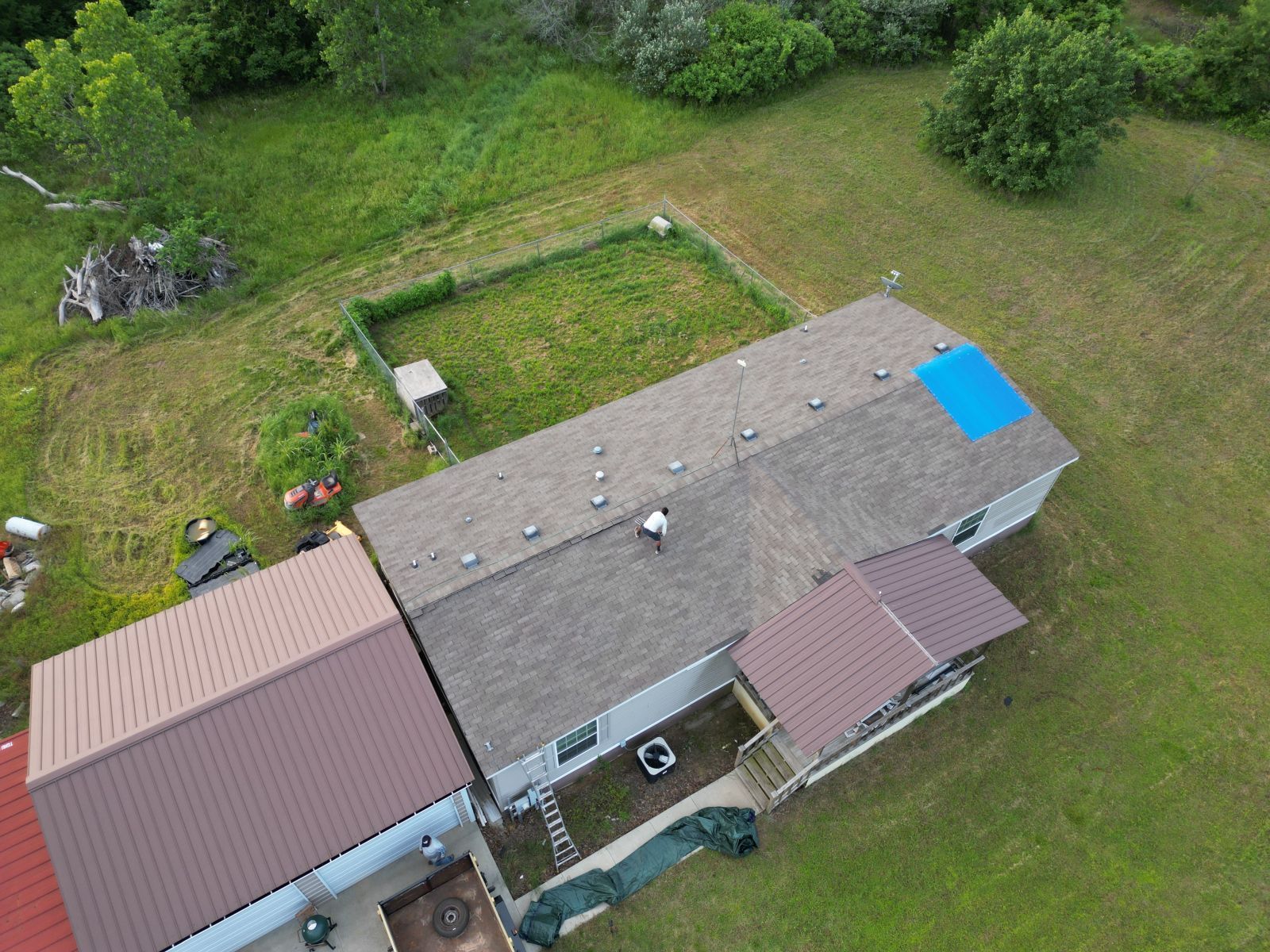 An aerial view of a house with a blue tarp on the roof.
