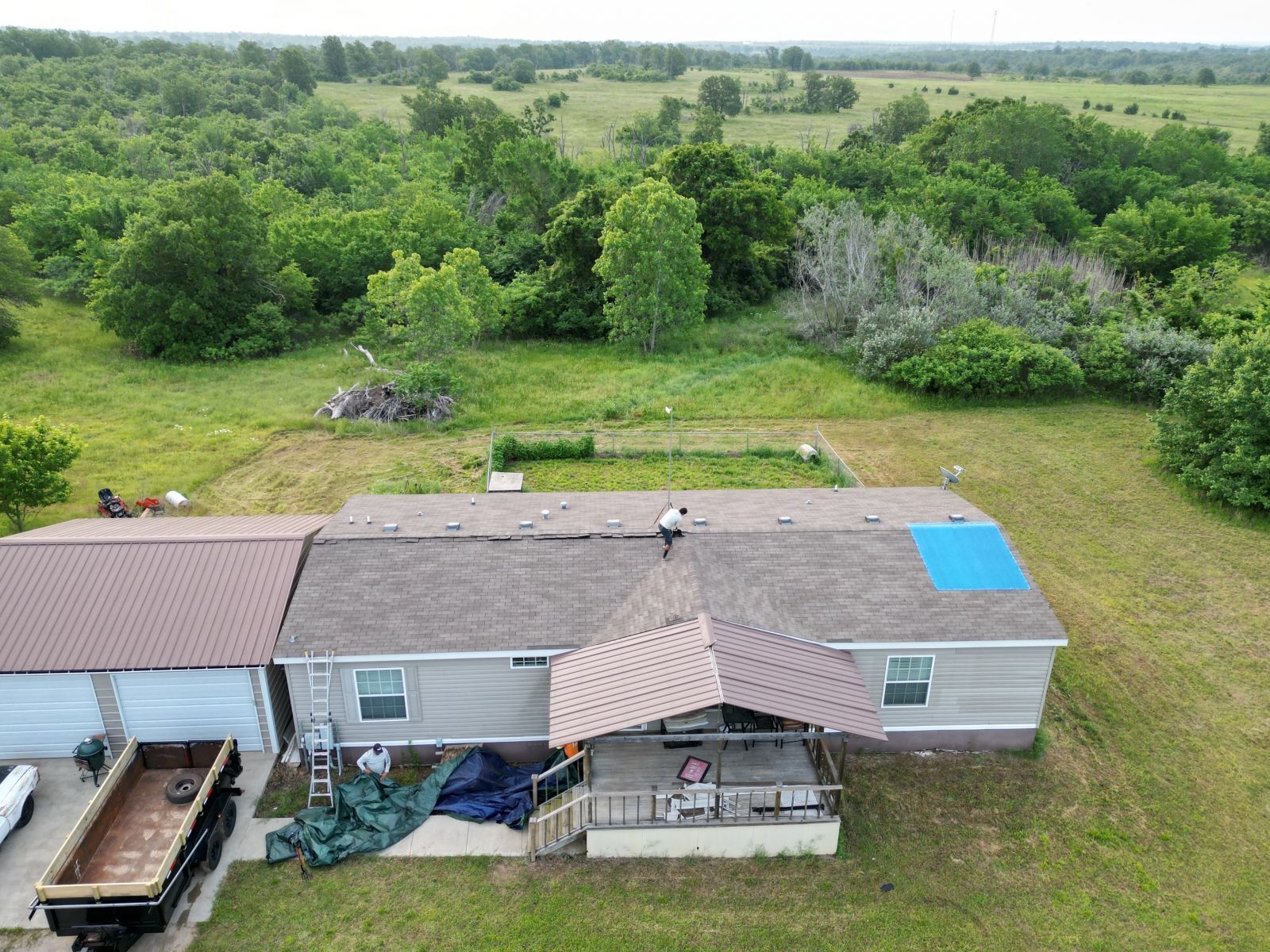 An aerial view of a house with a blue tarp on the roof.