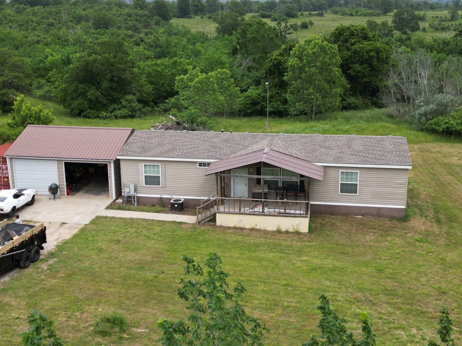 An aerial view of a mobile home in the middle of a grassy field.