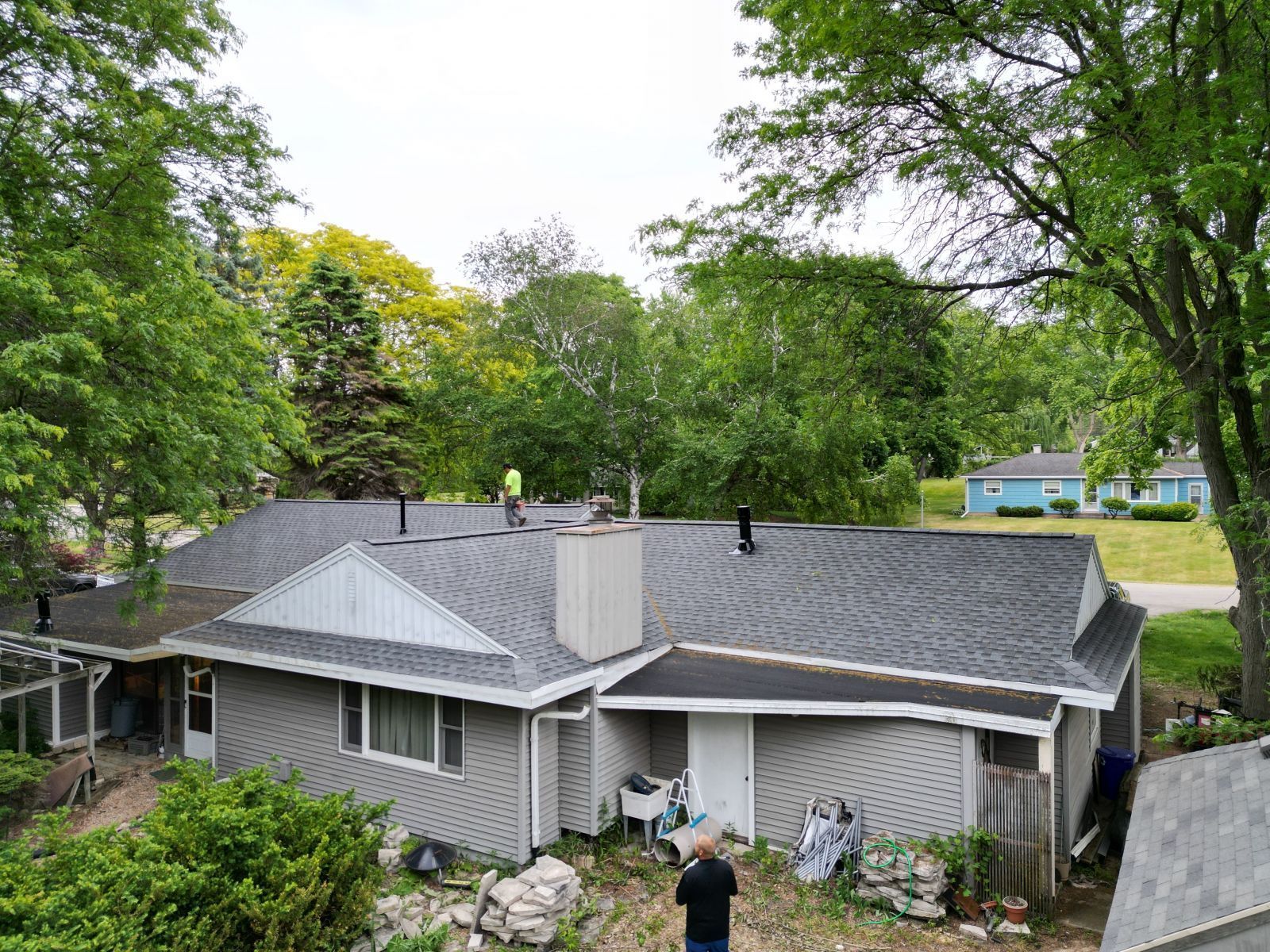 A man is standing in front of a house with a new roof.