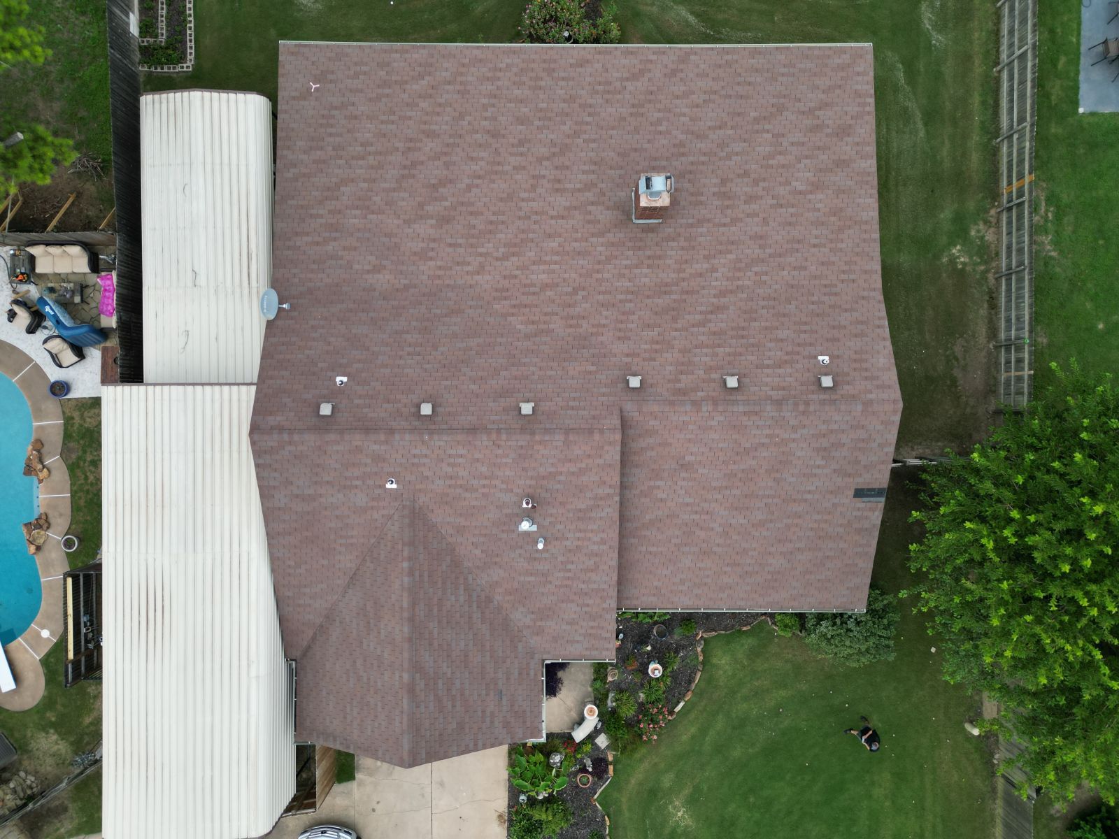 An aerial view of a house with a roof and a pool.