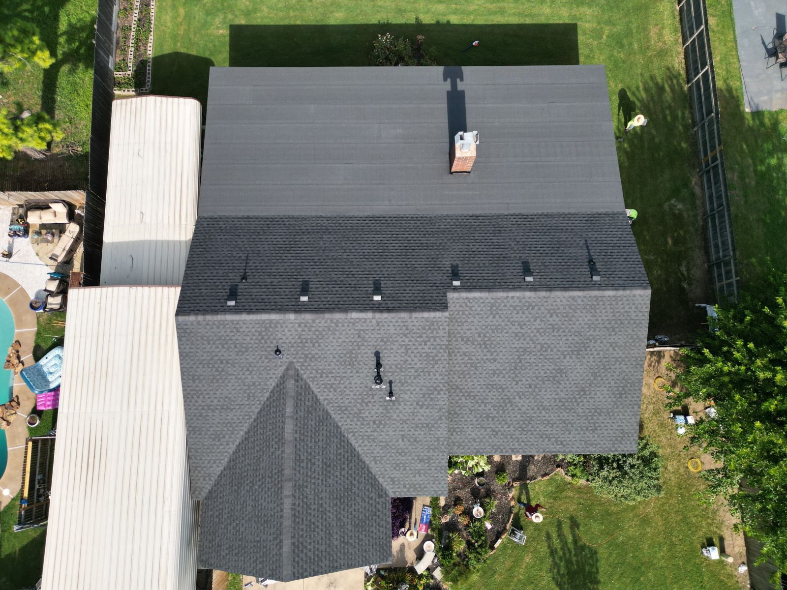 An aerial view of a house with a black roof and a chimney.