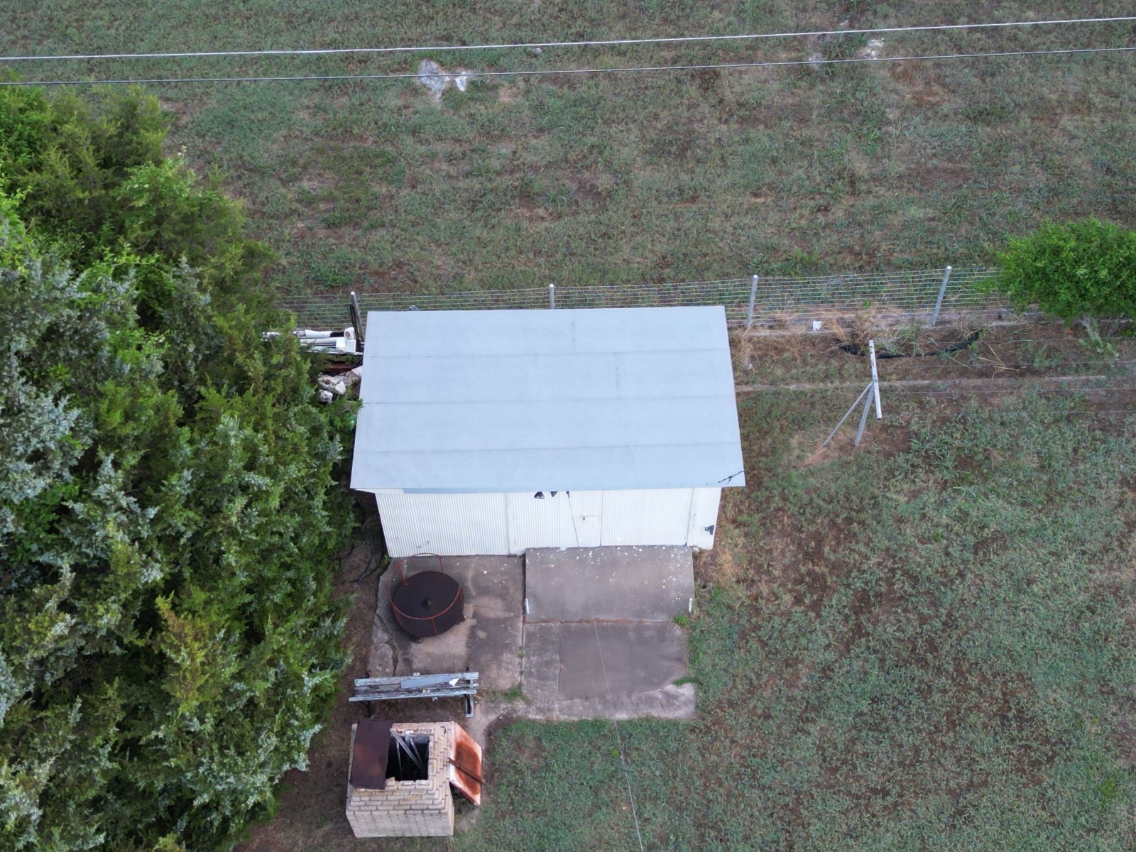 An aerial view of a shed in the middle of a field surrounded by trees.