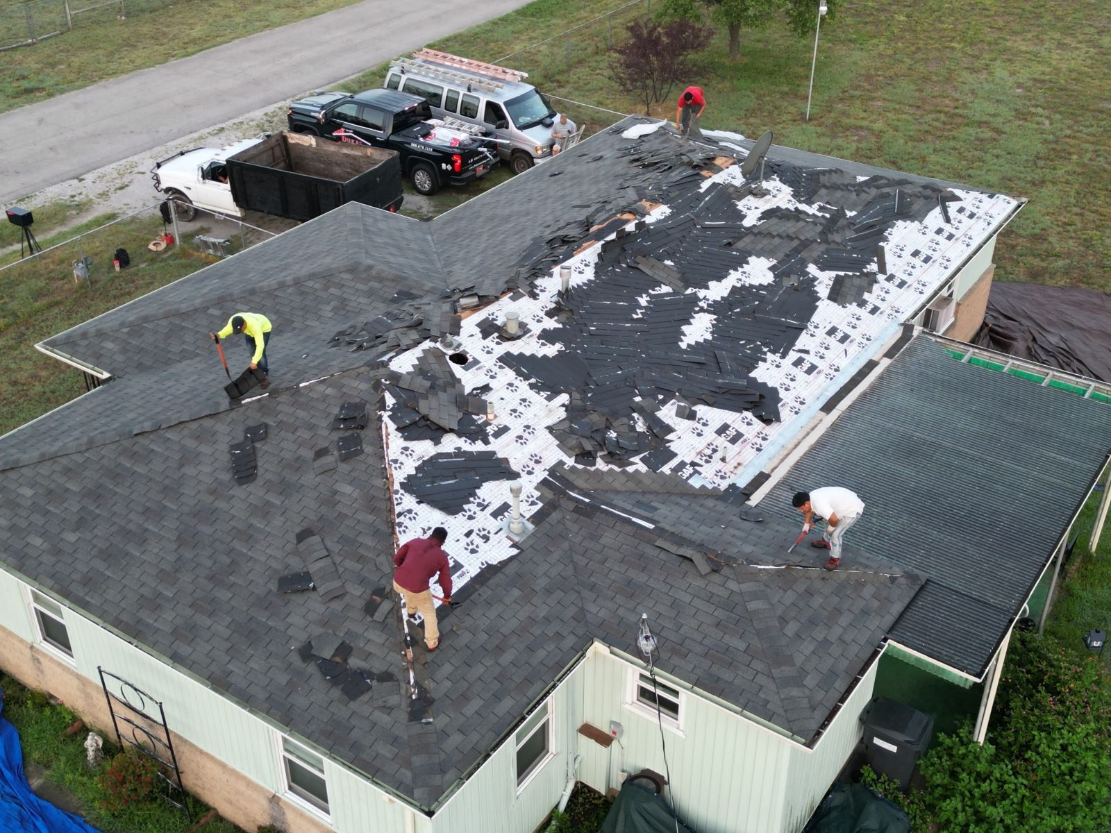 A group of people are working on the roof of a house.
