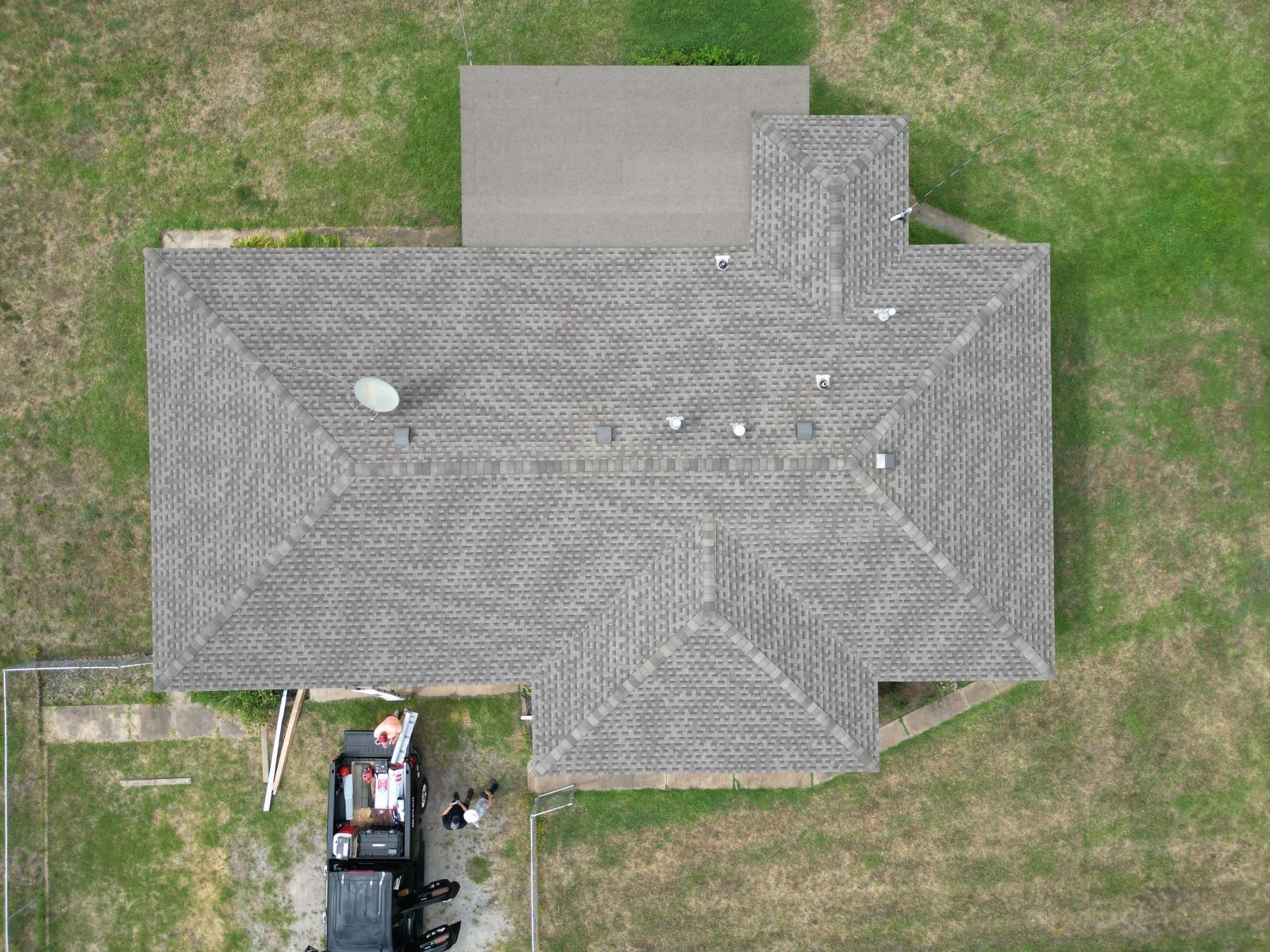 An aerial view of a house with a roof and a truck parked in front of it.