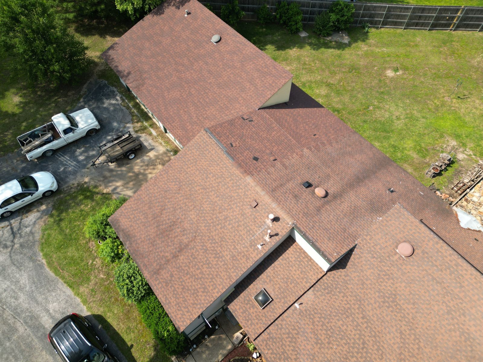 An aerial view of a house with two trucks parked in front of it.