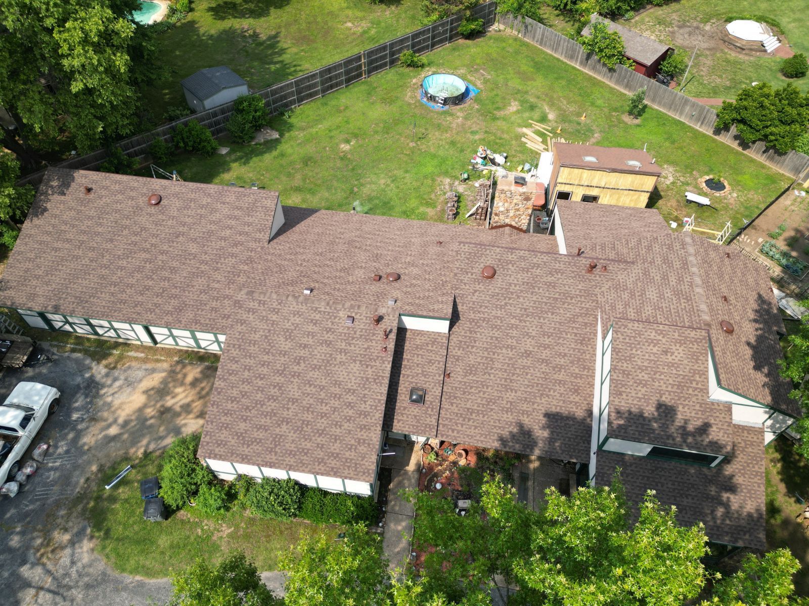 An aerial view of a house with a brown roof and a pool in the backyard.