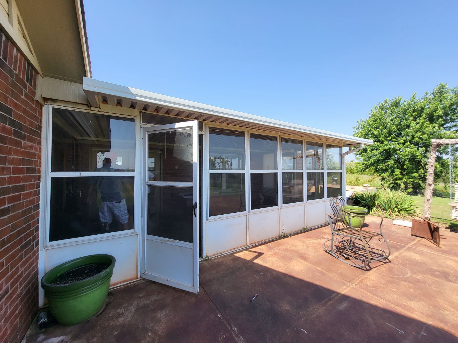 A screened in porch with a green pot in front of it.