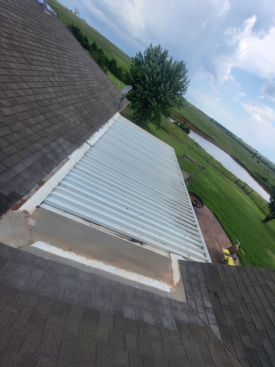 An aerial view of a roof with a metal roof and a river in the background.