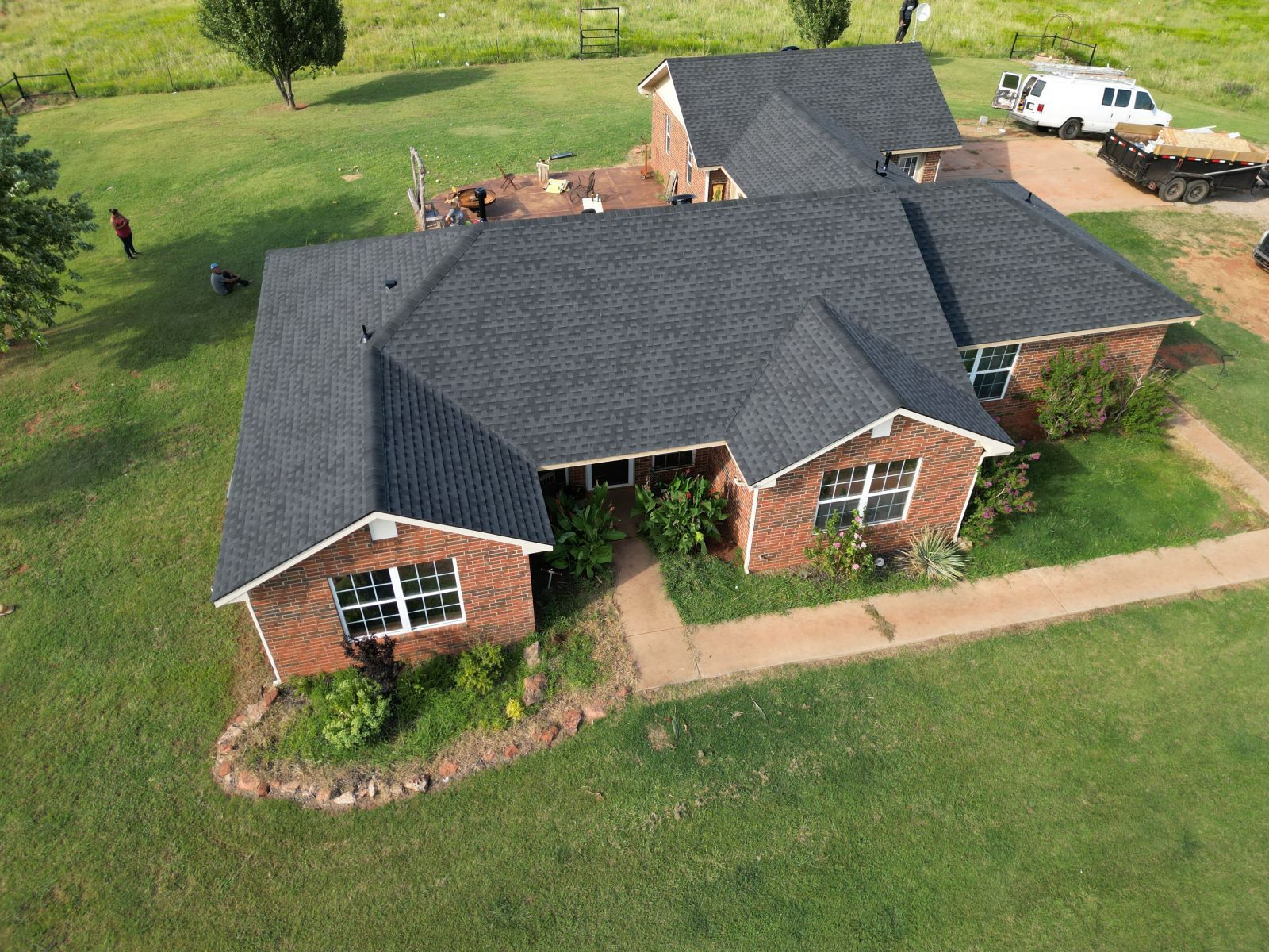 An aerial view of a large brick house with a black roof.