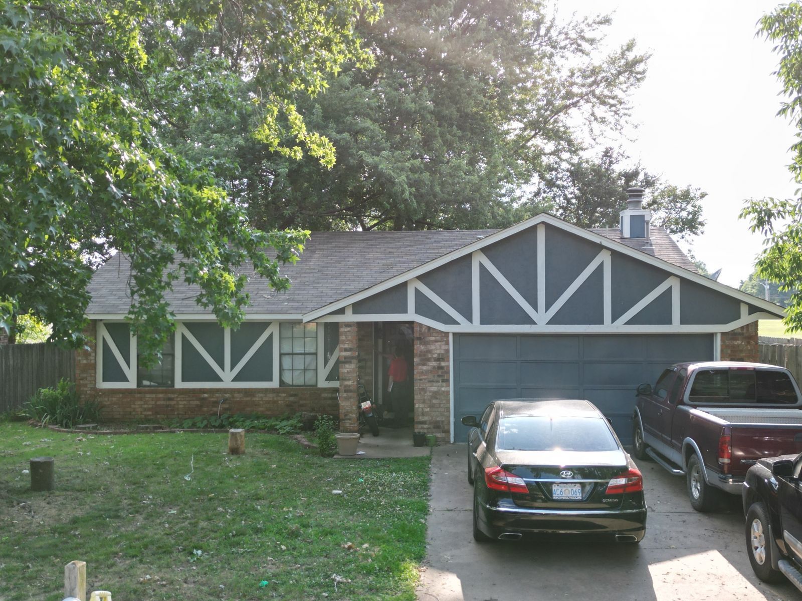 Two cars are parked in front of a house with the letter m on the front