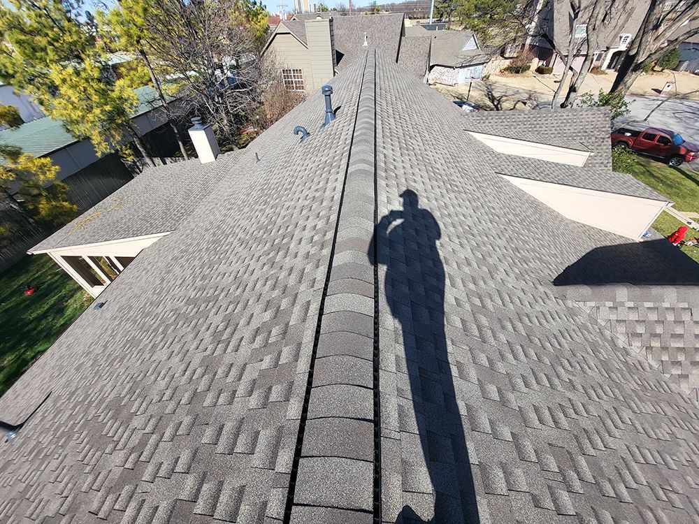 A shadow of a person is cast on the roof of a house.