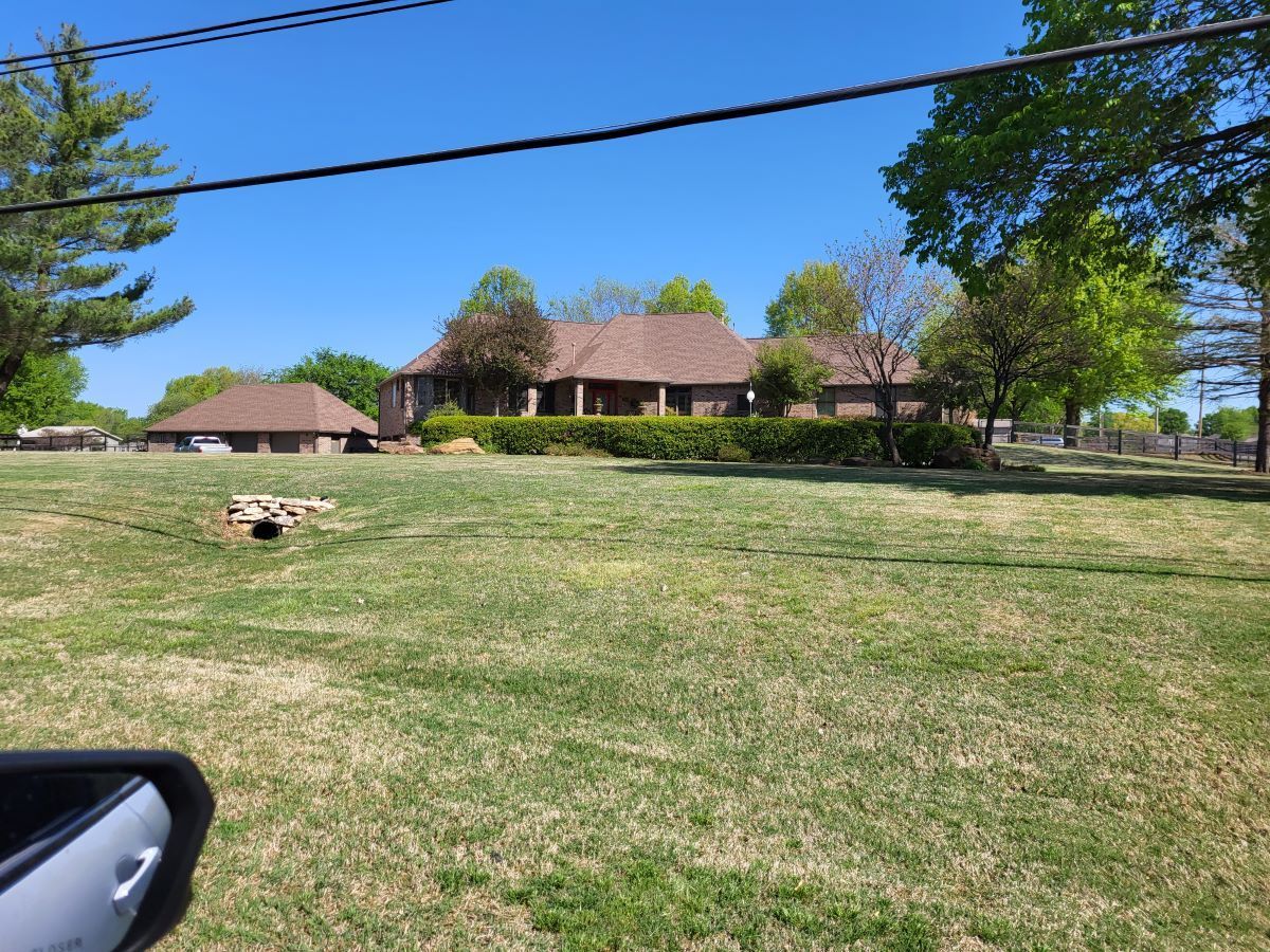 A large house is sitting in the middle of a lush green field.
