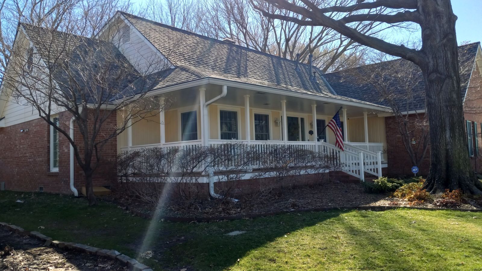 A brick house with a porch and an american flag on it