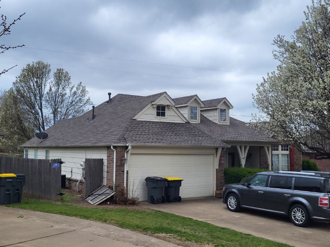 A car is parked in front of a house on a cloudy day.