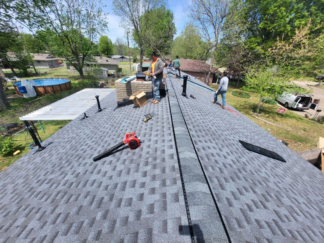 A group of people are working on a roof of a house.