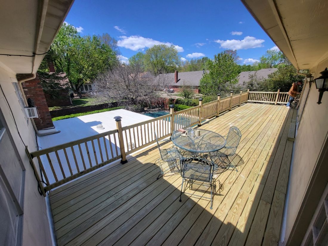 A large wooden deck with a table and chairs on it