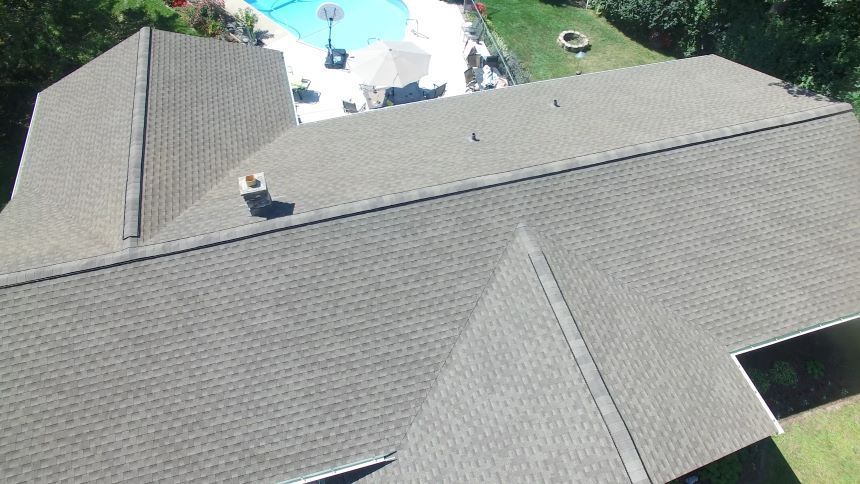 An aerial view of a roof of a house with a pool in the background.