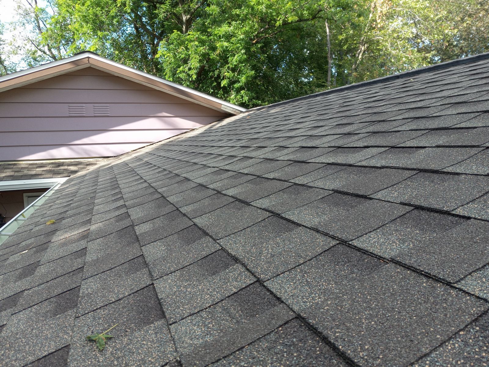 A close up of a roof of a house with trees in the background.