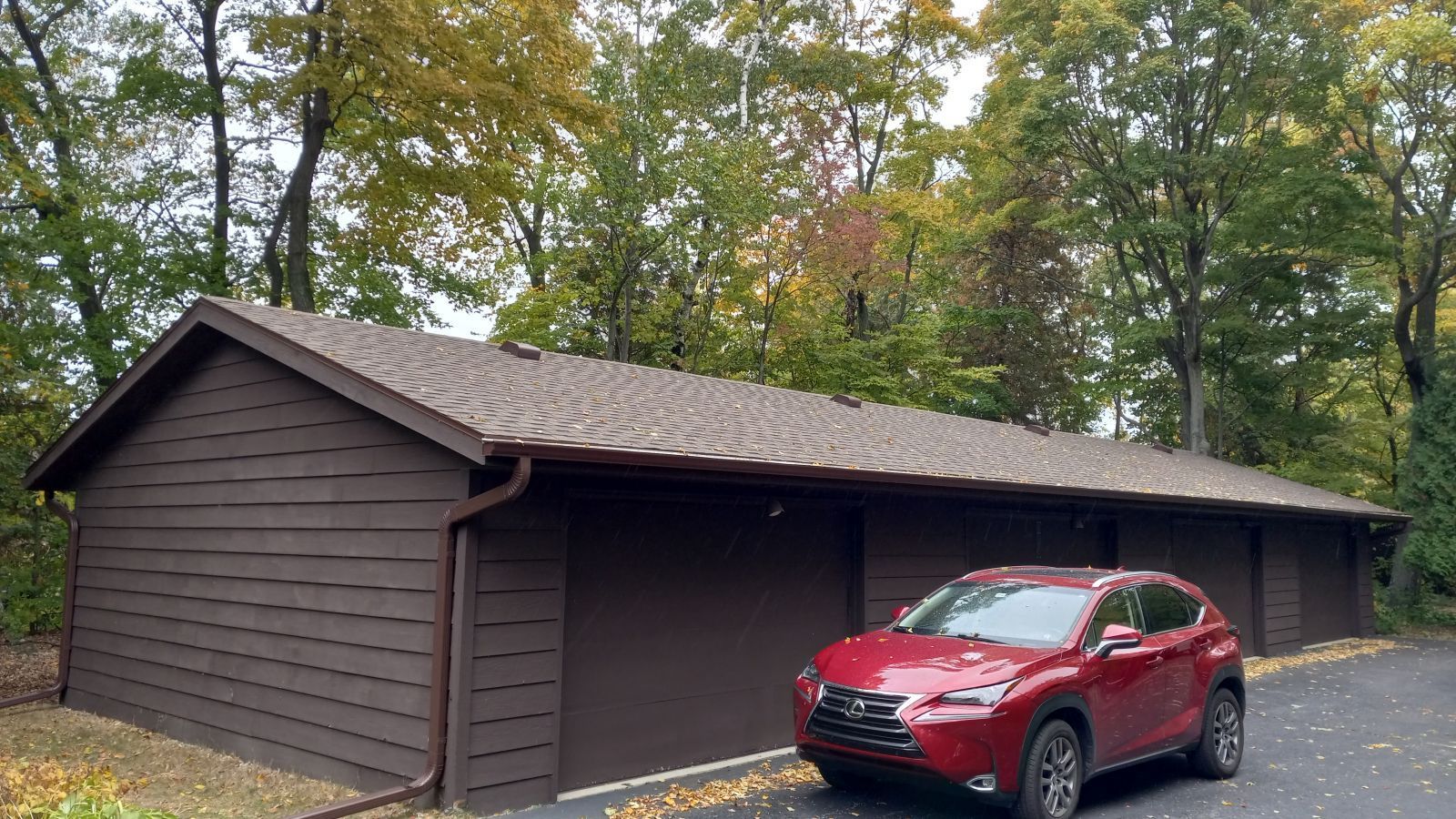 A red car is parked in front of a garage.