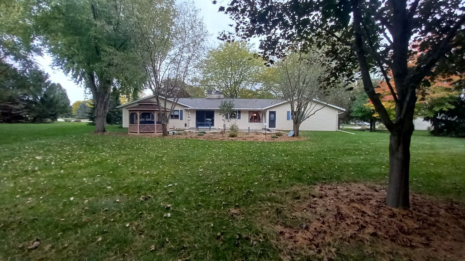 A house with a large lawn and trees in front of it.