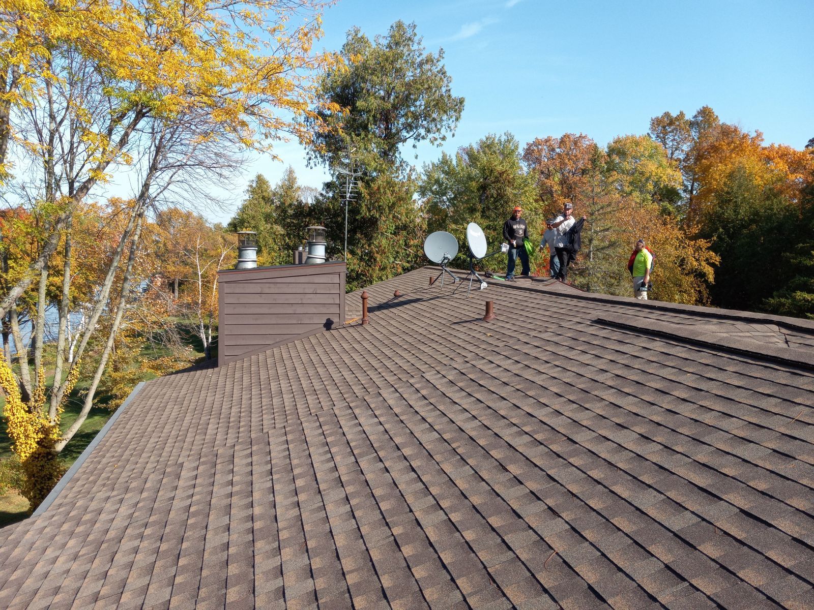 A group of people standing on top of a roof with satellite dishes.
