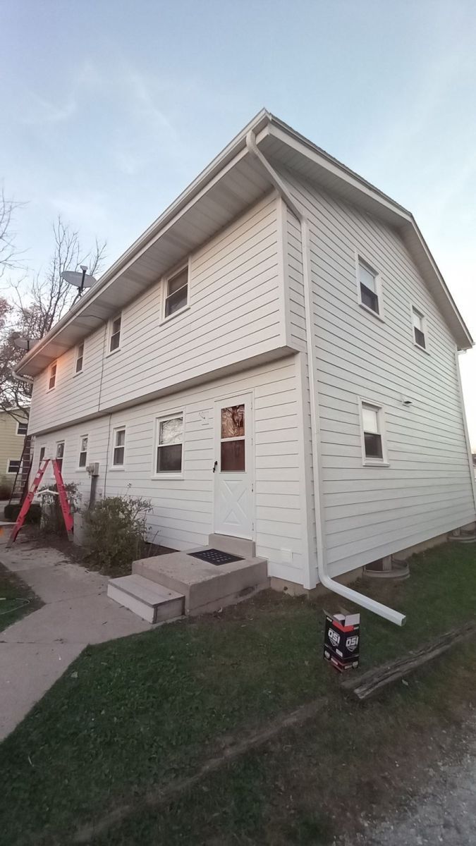 A white house with a ladder in front of it is being painted.