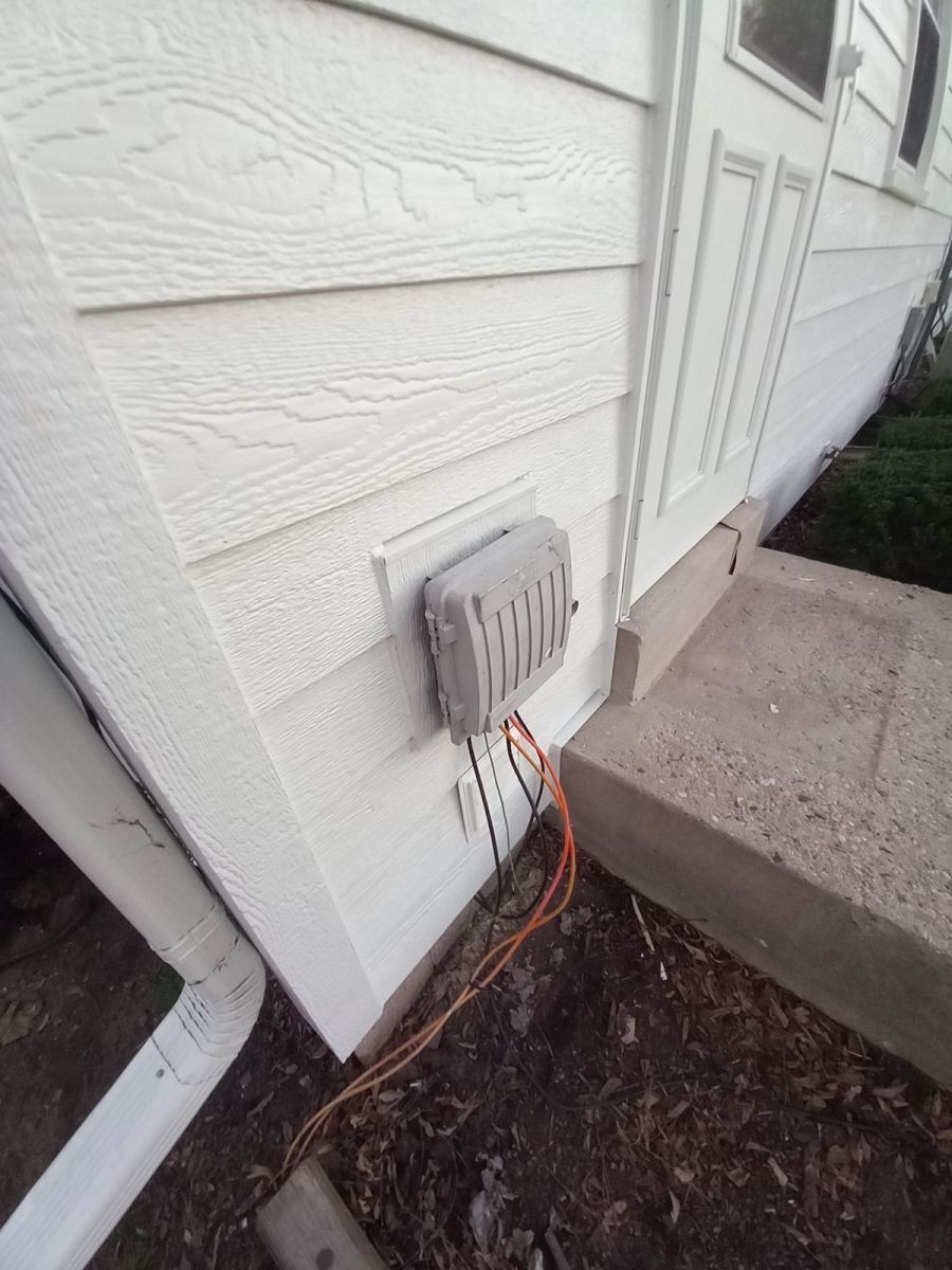 A white house with a gray electrical box on the side of it.