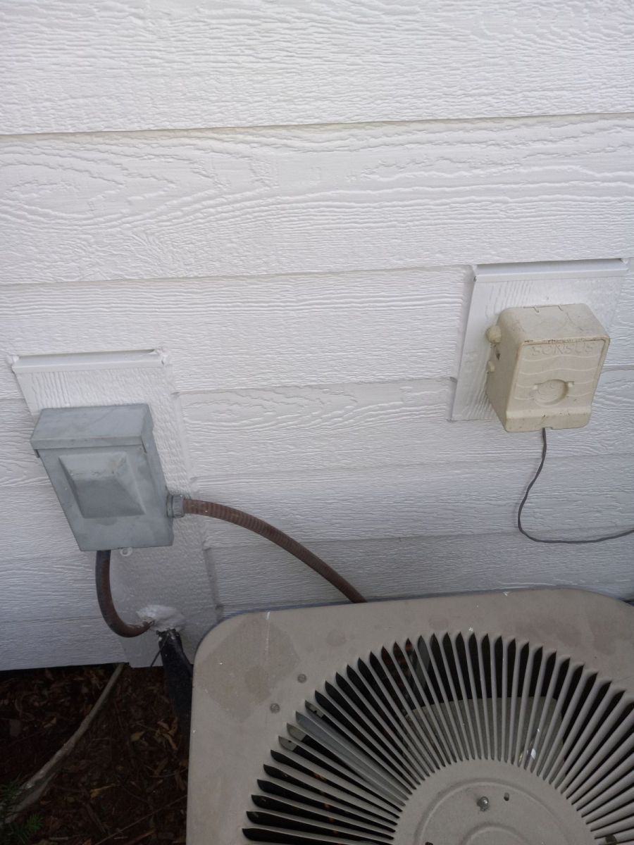 An air conditioner is attached to the side of a house