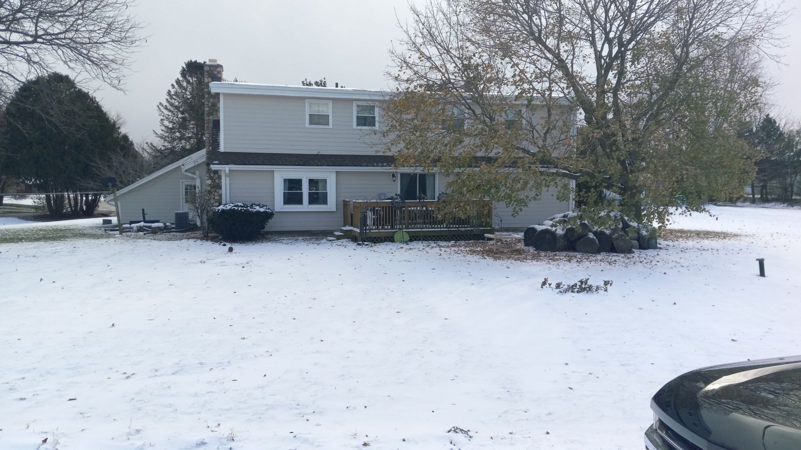 A house is covered in snow and a car is parked in front of it.