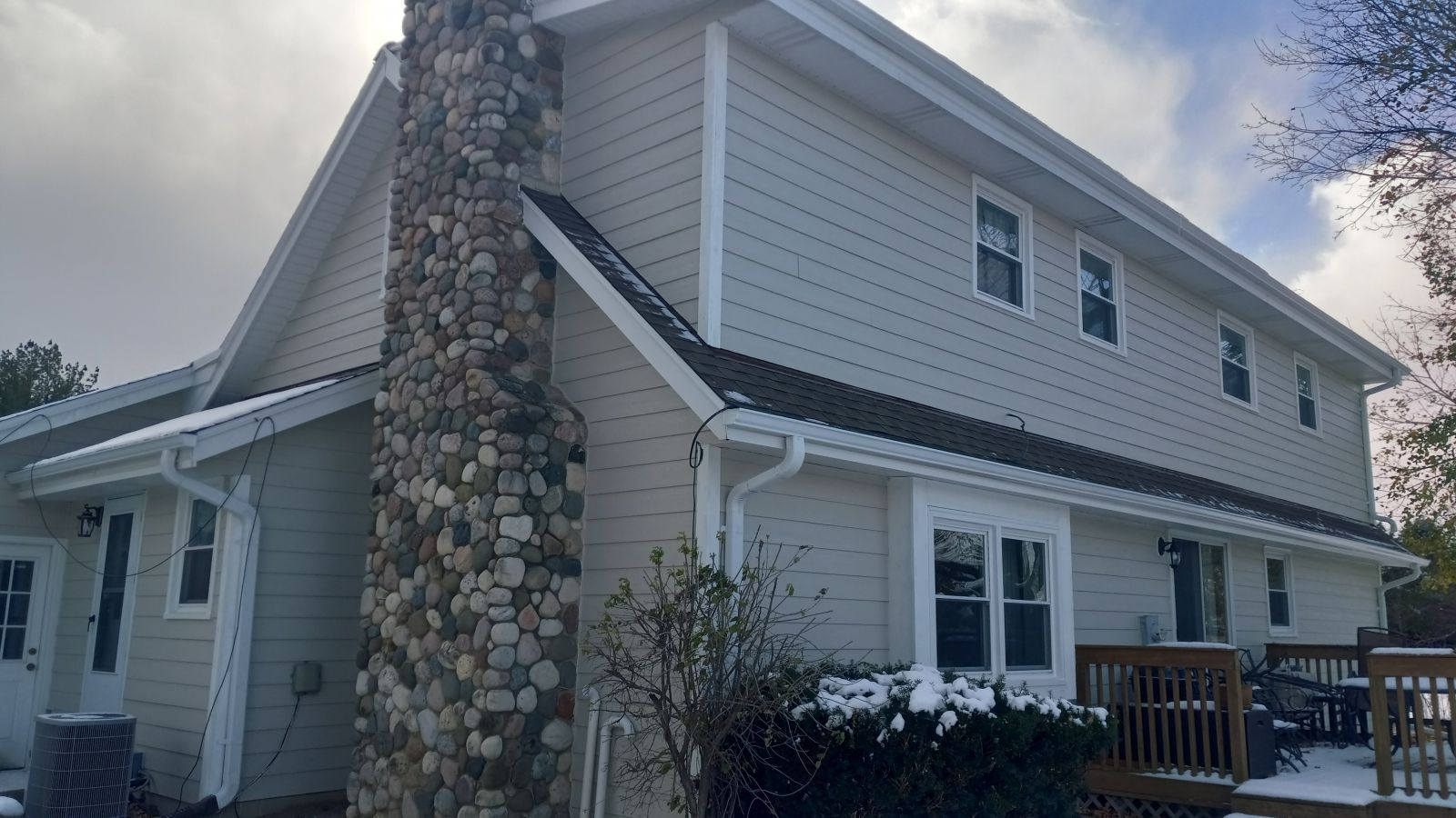 A large white house with a stone chimney on the side of it.
