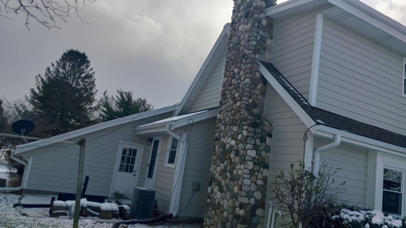 A white house with a chimney on the side of it in the snow.