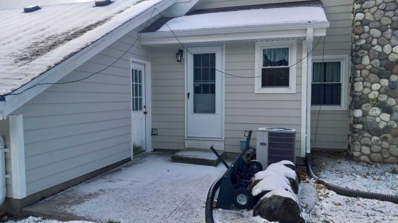 A house with a snow blower in front of it.