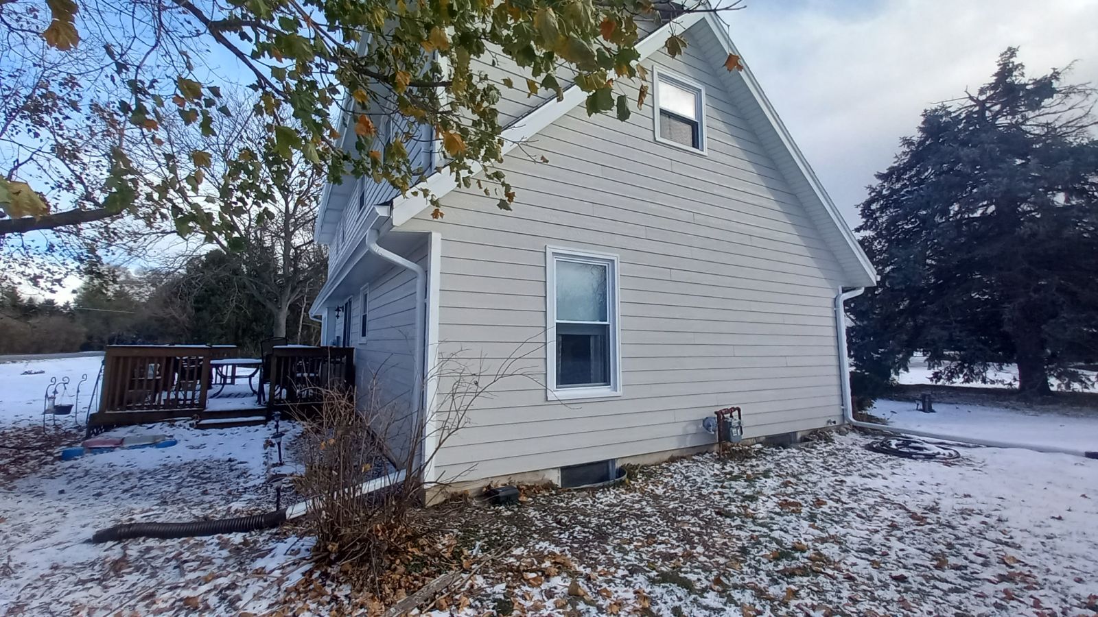 A white house is sitting in the middle of a snowy field.