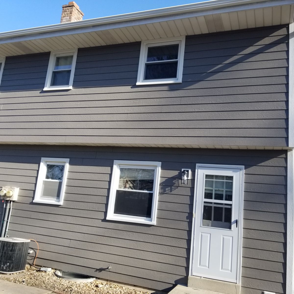 A gray house with a white door and windows