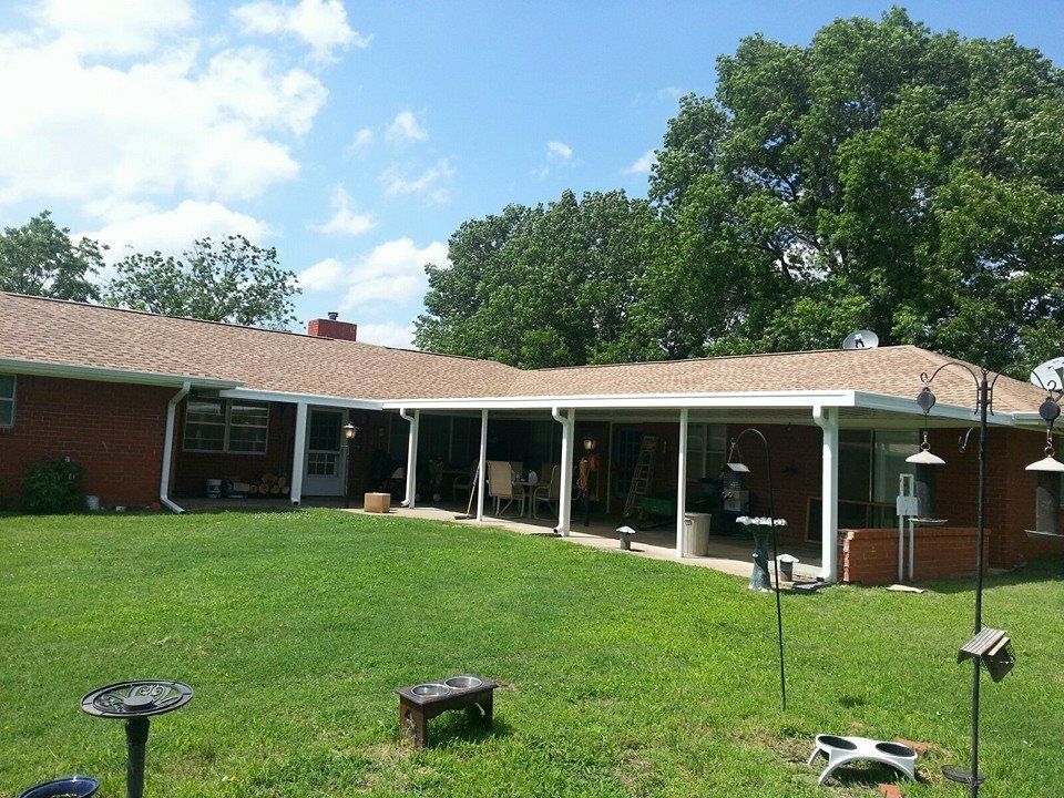 A brick house with a covered porch and a bird feeder in front of it