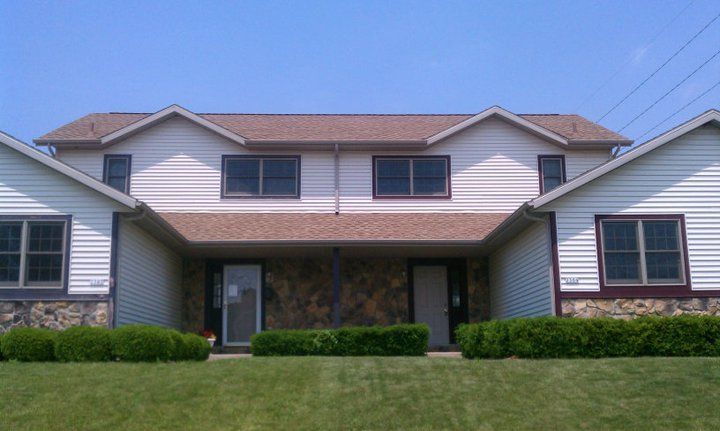 A white house with a brown roof and a lot of windows