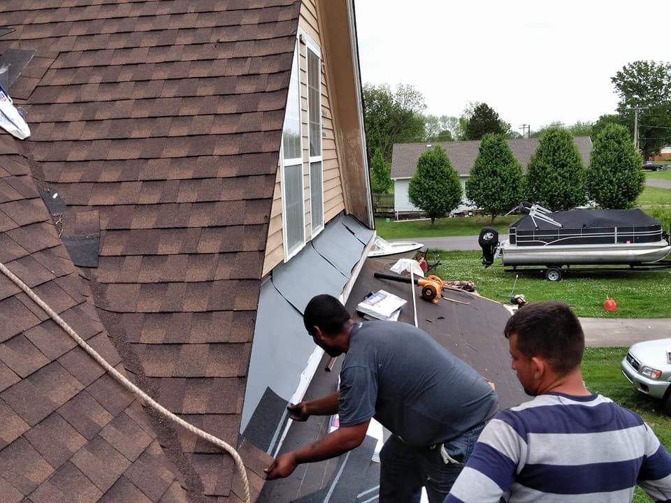 Two men are working on a roof with a boat in the background