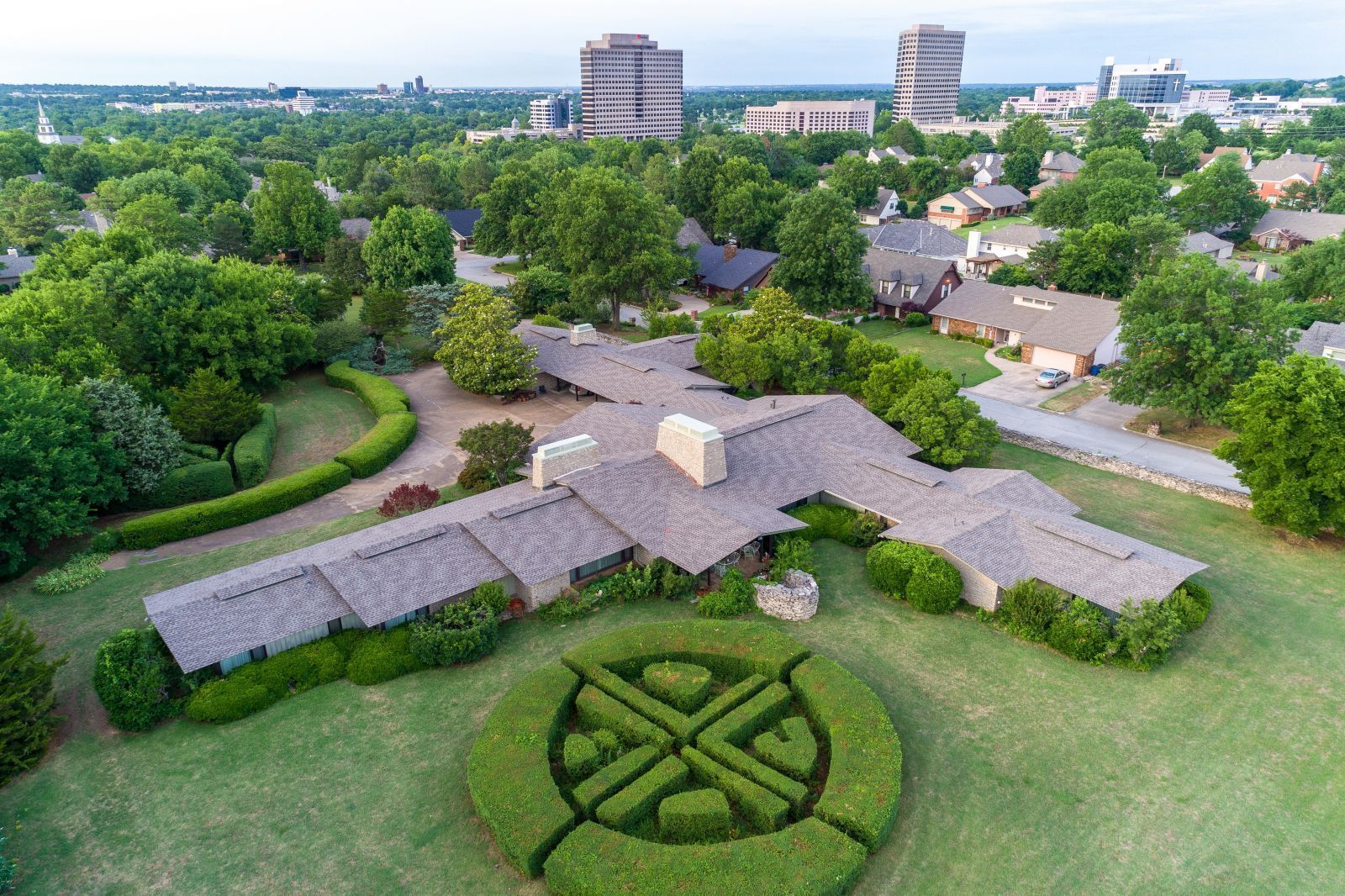 An aerial view of a large house surrounded by trees and bushes.
