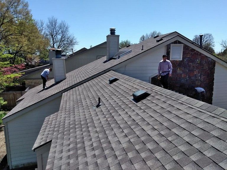 Two men are working on the roof of a house